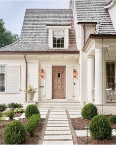 a white house with two large windows and steps leading up to the front door area