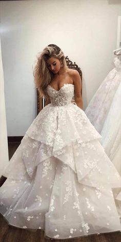 a woman standing in front of a mirror wearing a wedding dress with flowers on it