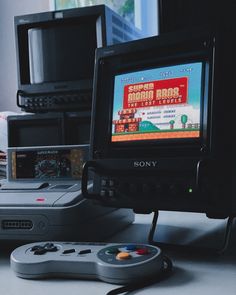 an old video game sitting on top of a table next to two other electronic devices