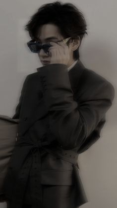 a man in a black suit and sunglasses holding a pillow with his hand to his face