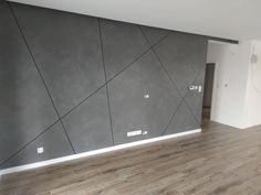 an empty room with wood floors and gray wallpaper on the walls, in front of a doorway