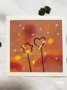 two dandelions in the shape of hearts on a pink background with sparklers