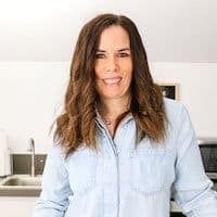 a woman is standing in the kitchen with her hands on her hips and smiling at the camera