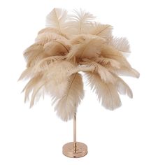 an ostrich feather arrangement on a gold stand against a white background with clippings