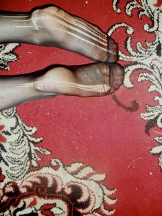 the feet of a person standing on a red and white carpet with ornate designs around them