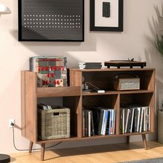 a book shelf with books and other items on it in a room next to a plant