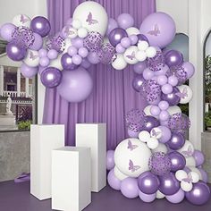 purple and white balloons are on display in front of a curtained room with curtains