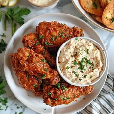 a plate with chicken wings, dip and crackers