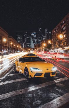 a yellow sports car parked on the side of a road in front of tall buildings