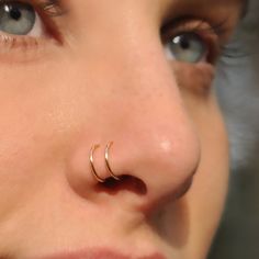 a close up of a person with a nose ring on their nose and one eye open