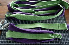 several pieces of purple and green fabric sitting on top of a table next to scissors