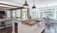 a large kitchen with an island in the middle and two pendant lights hanging from the ceiling