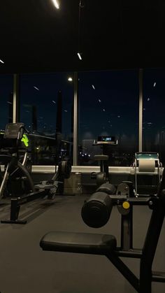 an empty gym room at night with treadmills and exercise equipment in the foreground