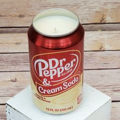 a can of cream soda sitting on top of a stack of books next to a candle