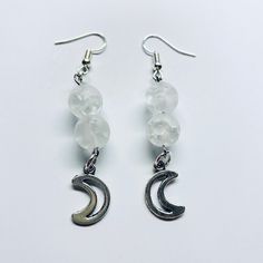 These beautiful dangle moon themed earrings are handmade with moon themed stone beads, moon charms, and silver fishhook ear wire.  They are approximately 2 inches long and are relatively lightweight. Every pair of earrings also comes with a complimentary organza bag and clear earring backs that stay on all day! These unique statement earrings have a super cool celestial vibe and go well with so many outfits! Get yours today for yourself or as a gift for a friend or family member! White Handmade Moon-shaped Earrings, Celestial Style White Hypoallergenic Earrings, White Celestial Hypoallergenic Earrings, Crystal Moon Earrings With Moon Charm As Gift, Moon Shaped Crystal Earrings With Moon Charm As Gift, Gift Crystal Moon Earrings With Moon Charm, Moon-shaped Crystal Earrings With Moon Charm As Gift, Adjustable Moon-shaped Moonstone Earrings, Nickel-free Moonstone Moon Earrings