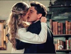 a man and woman kissing in front of bookshelves