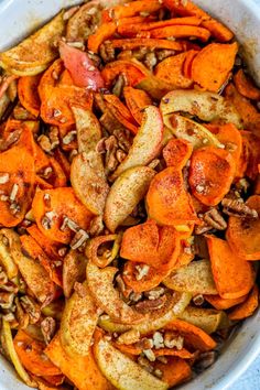 a white bowl filled with sliced carrots and pecans on top of a table