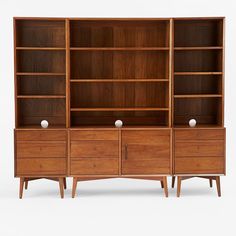 a wooden bookcase with drawers and two white balls on the bottom shelf, against a white background