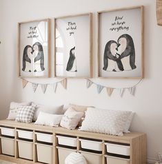 three framed pictures hang on the wall above a bench with pillows and storage bins