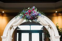 an arch decorated with flowers and greenery is seen in this image from the front