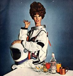 a woman dressed in an astronaut suit sitting next to bottles and glasses