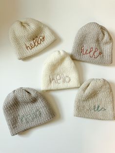 four knitted hats with the word hello written on them