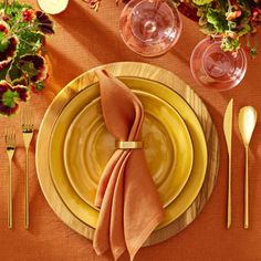 a place setting with orange napkins and yellow plates