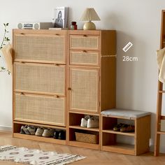 a wooden cabinet with baskets and shoes on it next to a rug in a room