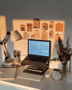 a laptop computer sitting on top of a desk next to a lamp and other office supplies