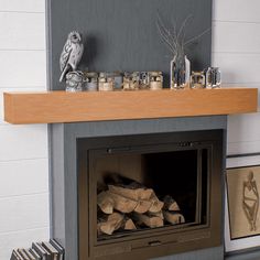 a fire place with wood logs on the mantle and an owl figurine above it