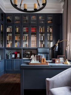 a home office with built in bookshelves and blue cabinets