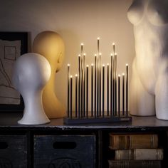 there are many candles on the table next to some mannequins and books