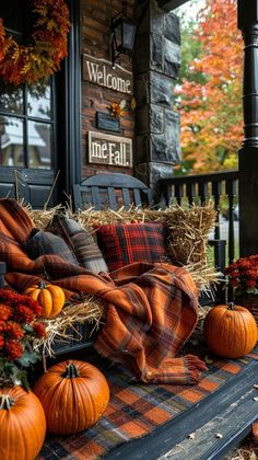 pumpkins and hay bales are arranged on the front porch