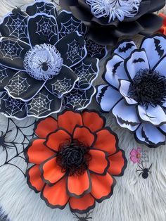 four paper flowers are sitting on a white furnishing with black and orange accents