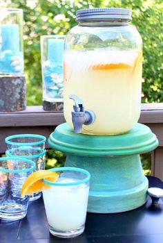 there is a pitcher on top of a table with glasses and cups next to it