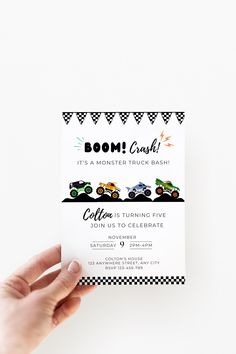 a person holding up a card with a monster truck on the front and bottom, which reads boom crash it's a monster truck bash before turning five john us to celebrate