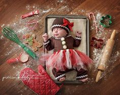 a baby in a red and white tutu laying on top of a cookie sheet