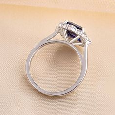 a diamond and sapphire engagement ring on a beige surface with the center stone in white gold