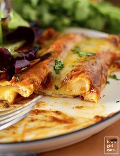 a white plate topped with lasagna covered in cheese and sauce next to a salad