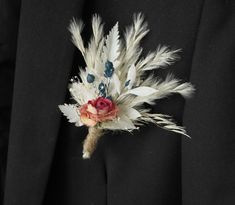 a boutonniere with feathers and flowers on it's lapel pin