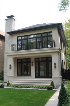 a white house with black windows and balconies on the second floor is shown