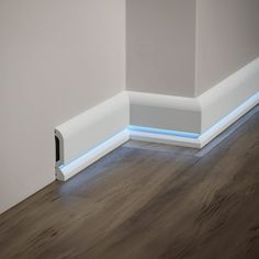 the corner of a room with wood flooring and white painted trim on the wall