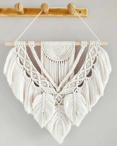 a macrame wall hanging with tassels and wooden pegs on it