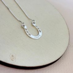 Add a touch of elegance and good luck to your jewelry collection with this custom Horseshoe Necklace. Crafted in high-quality sterling silver, this personalized necklace features a beautifully crafted horseshoe pendant, engraved with a word or name in an elegant font. The horseshoe is a timeless symbol of luck and protection. Wearing a horseshoe pendant is believed to bring good fortune and safeguard the wearer from negative energy. Our horseshoe pendant necklace makes a thoughtful and meaningfu