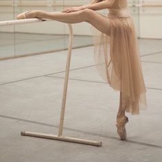 a ballerina is standing on one leg and holding the bar