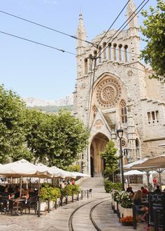 people sitting at tables in front of an old church