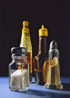 three glass bottles filled with different types of condiments