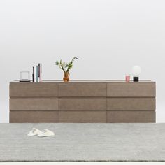 a vase with flowers on top of a wooden dresser next to a pair of shoes