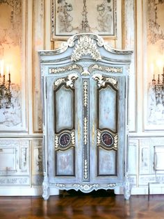 an ornate white and blue armoire in a room