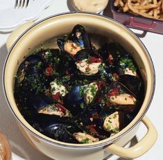 a pot filled with mussels and sauce on top of a table